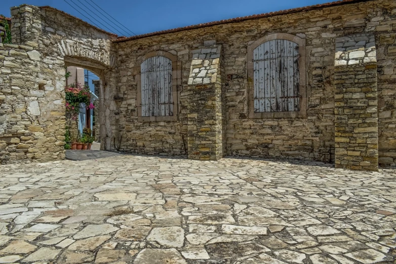 a red fire hydrant sitting in front of a stone building, by Michalis Oikonomou, romanesque, greek fantasy panorama, mosaic stone floor, in a village street, cyprus