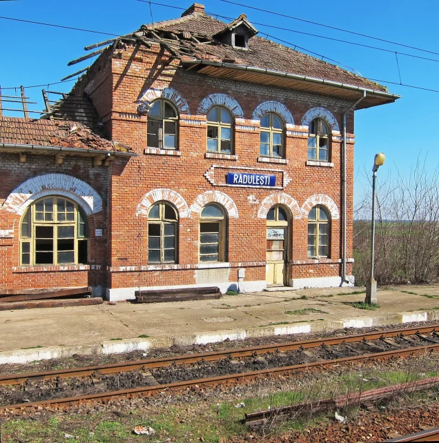 a train station sitting next to a train track, by Serhii Vasylkivsky, regionalism, brick building, deteriorated, front side view, very accurate photo