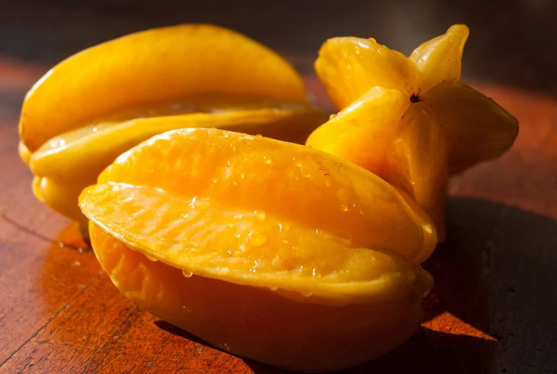 a couple of oranges sitting on top of a wooden table, mango, yellow colors, chili, lush paradise