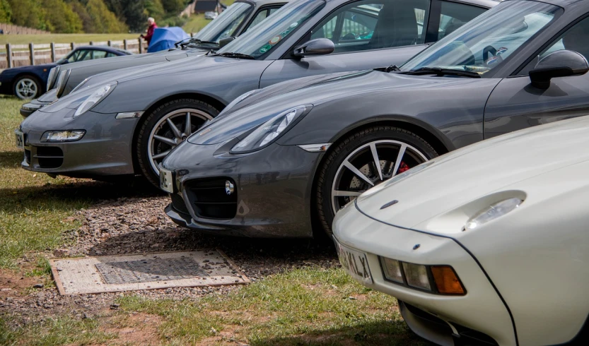 a row of sports cars parked next to each other, by Richard Carline, grey and silver, zoomed in, 2 4 mm iso 8 0 0, gravels around