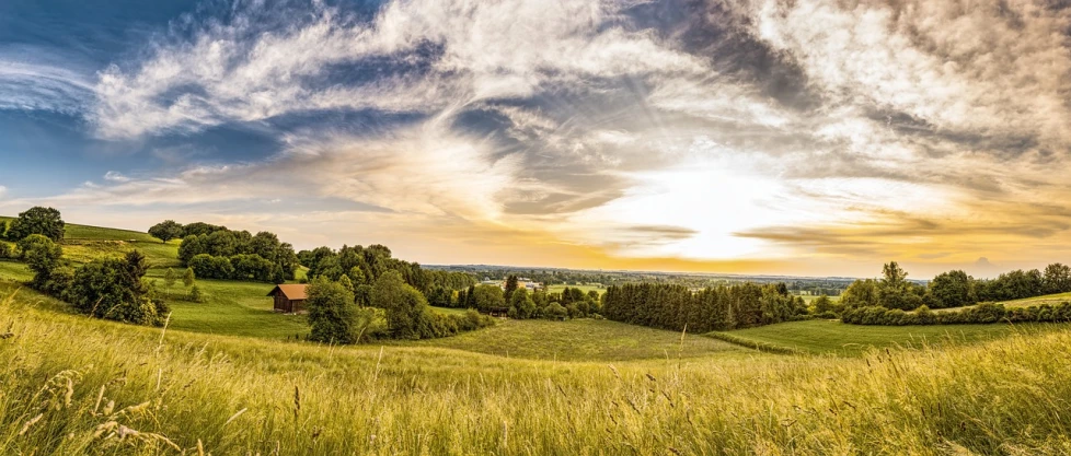 a house sitting on top of a lush green hillside, a picture, by Thomas Häfner, shutterstock, sunset panorama, wide view of a farm, summer field, wide angle shot 4 k hdr