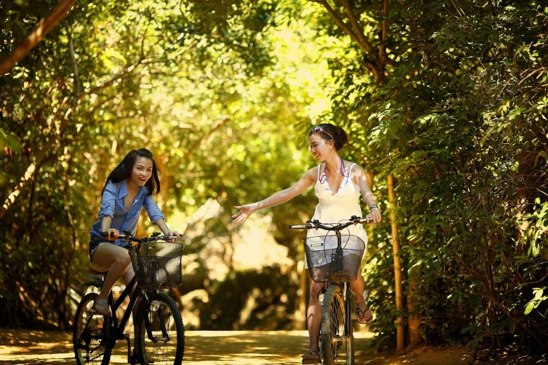 a couple of women riding bikes down a dirt road, shutterstock, sunny day in a park, talking, a green, ca