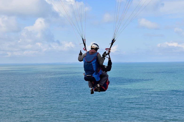 a man flying through the air on top of a parachute, a photo, by Alison Watt, shutterstock, over the ocean, couple, 4k footage, konstantin porubov