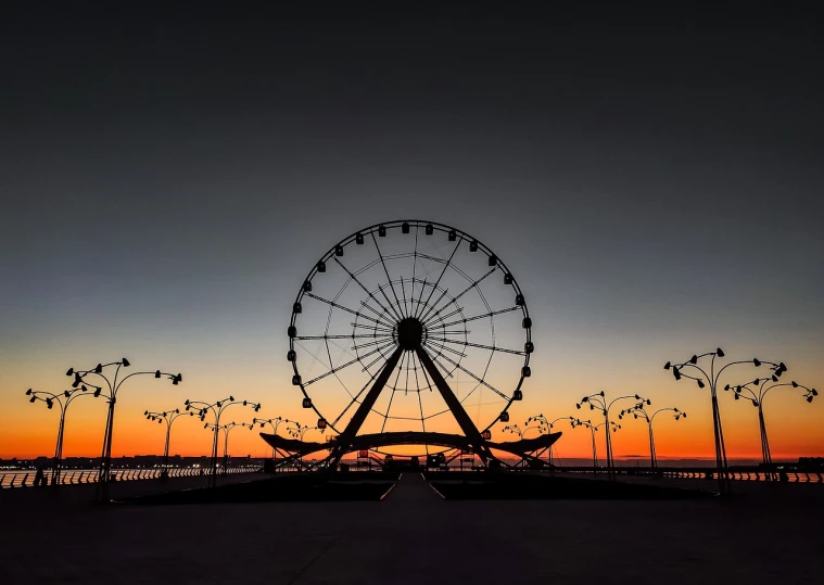 a ferris wheel sitting on top of a sandy beach, a picture, by Andrei Kolkoutine, pexels contest winner, romanticism, city sunset night, at sunrise in springtime, magnificent super wide angle, an ancient