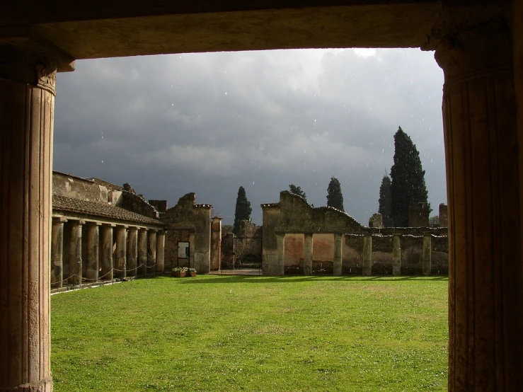 a view of an ancient building through a doorway, by Pogus Caesar, flickr, it\'s raining, a wide open courtyard in an epic, pompeian, cumulonimbus