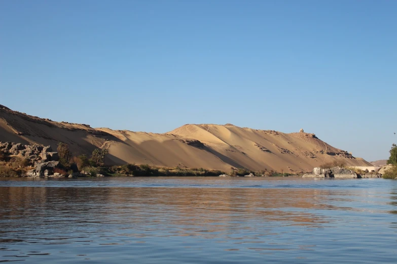 a body of water with sand hills in the background, a picture, by Robert Zünd, flickr, les nabis, the key of the nile, the photo was taken from a boat, hill, the morning river