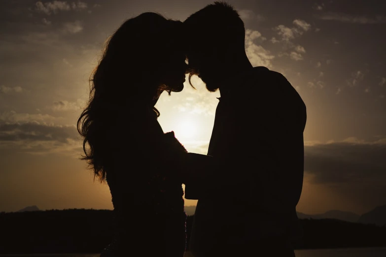 a couple standing next to each other in front of a sunset, romanticism, intimately holding close, uploaded, silhuette, romantic lead