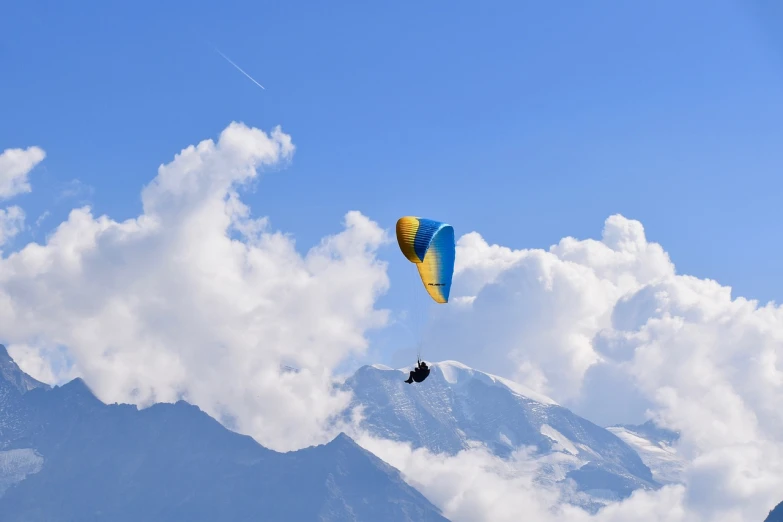 a person that is flying a kite in the sky, a picture, by Werner Andermatt, shutterstock, chamonix, parachutes, on clouds, 2 colors