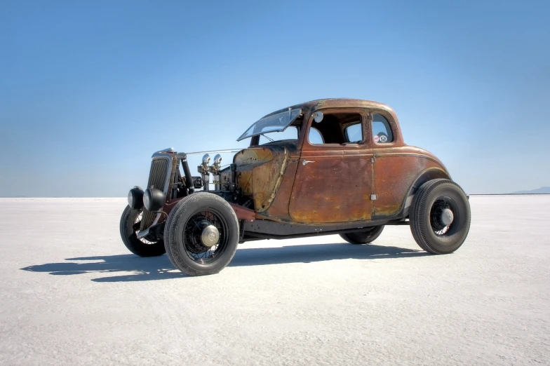 an old rusty car sitting in the middle of the desert, by Murray Tinkelman, auto-destructive art, driving a hotrod, wide full body, covered in salt, lane brown