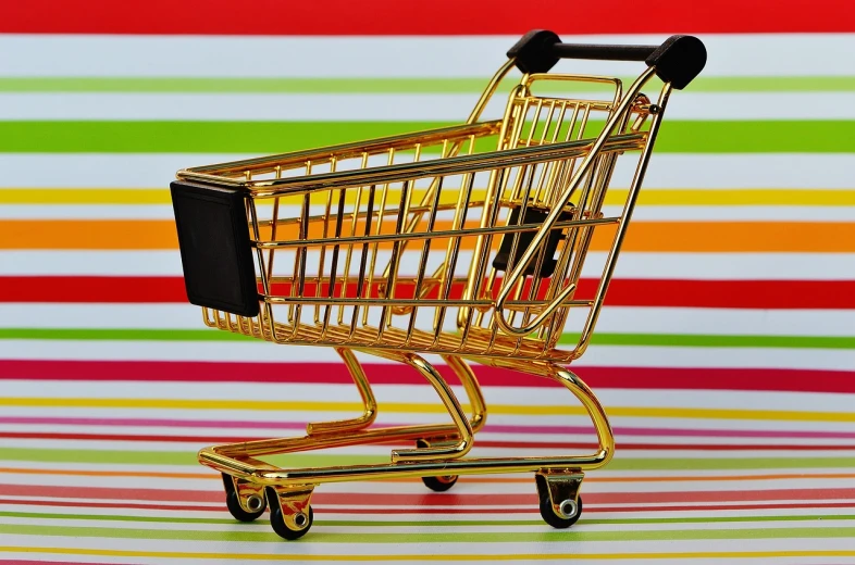 a miniature shopping cart sitting on top of a table, by Harold Elliott, pixabay, maximalism, striped, shiny gold, vibrant setting, rack