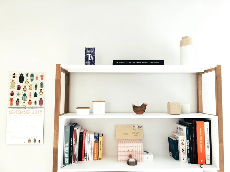 a white book shelf filled with lots of books, a picture, unsplash, minimalism, decorations, product introduction photo, bulky build, brightly lit room