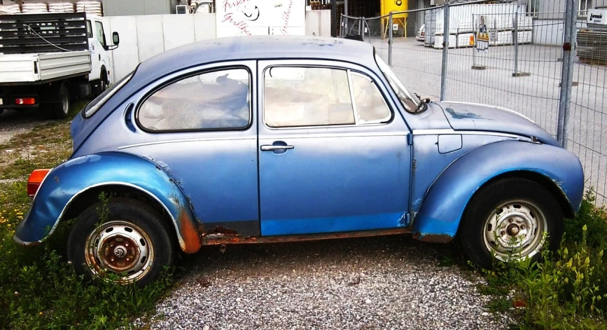 an old blue car is parked on the side of the road, a photo, by Werner Gutzeit, auto-destructive art, john lennon as a stag beetle, photo of poor condition, ebay photo, kreuzberg