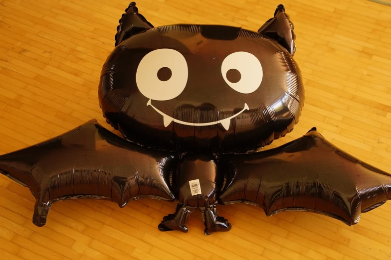 a balloon shaped like a bat on a wooden floor, a cartoon, flickr, sōsaku hanga, inflateble shapes, happy cat, very detailed picture, spooky photo