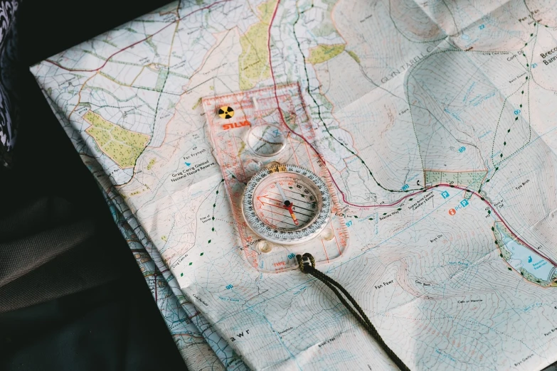 a compass sitting on top of a map, a photo, by Emma Andijewska, utilitarian, 🦑 design, seams, camp