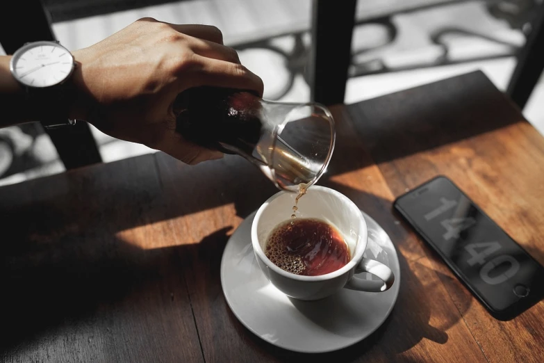 a person pours liquid into a cup of coffee, by Adriaen Hanneman, pexels, photorealism, stock photo, istock, taken on iphone 14 pro, cafe