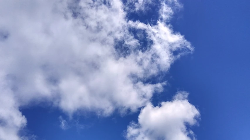 a large jetliner flying through a cloudy blue sky, a picture, by Jan Rustem, precisionism, cell phone photo, sitting in a fluffy cloud, viewed from below, cloudless-crear-sky