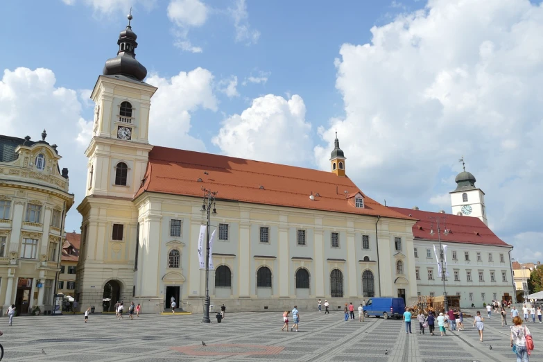 a large white building with a clock tower, inspired by Slava Raškaj, old abbey in the background, crowded square, mustard, luminist and baroque style