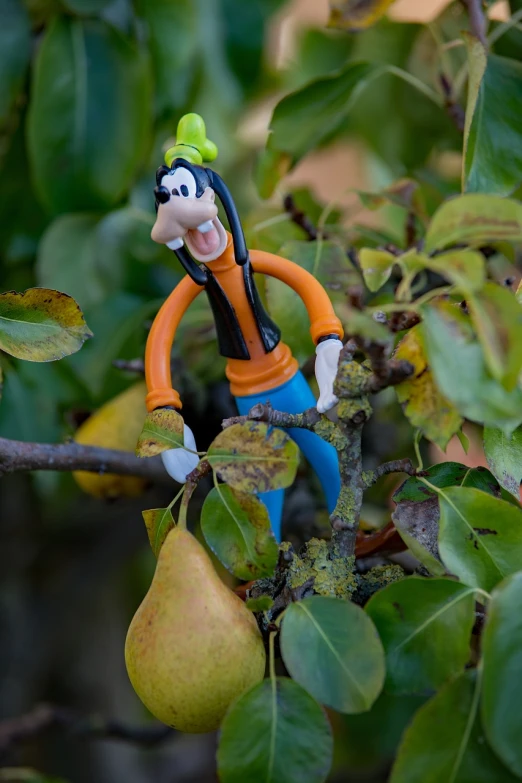 a figurine sitting on top of a tree branch next to a pear, inspired by Pál Böhm, pexels, figuration libre, loony toons style, goofy smile, full frame shot, mini model