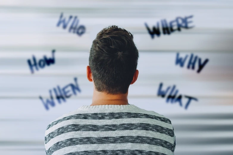 a man standing in front of a wall with writing on it, a picture, close-up shot from behind, procrastination, distant thoughtful look, blurred photo