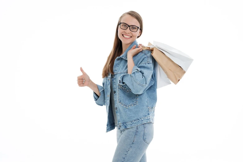 a woman holding shopping bags and giving a thumbs up, a stock photo, by Aleksander Gierymski, shutterstock, figuration libre, wearing thin large round glasses, wearing a jeans jackets, with a white background, high quality product photo