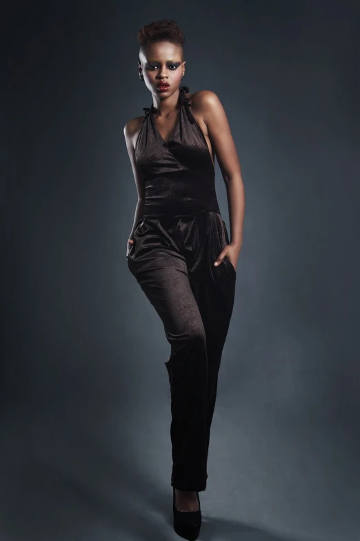 a woman in a black dress posing for a picture, trending on cg society, harlem renaissance, jumpsuit, studio!! portrait lighting, curves!!, low iso