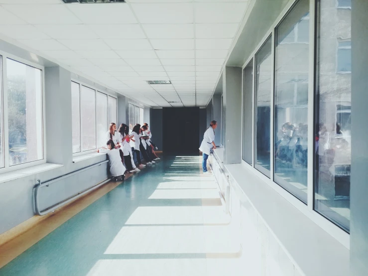 a group of people walking down a long hallway, a picture, by Matija Jama, pexels, happening, nurse scrubs, the window is open, sitting in an empty white room, photo taken with an iphone