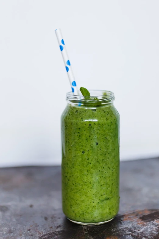 a jar of green smoothie with a blue and white striped straw, a portrait, by Juan O'Gorman, unsplash, green legs, slightly overexposed, bottle, taken with a pentax1000