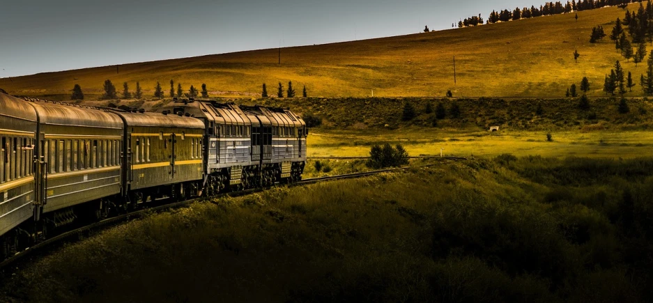 a large long train on a steel track, by Jesper Knudsen, golden grasslands, with rolling hills, stylized photo, header