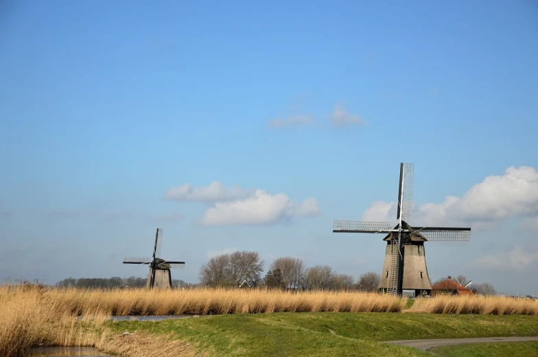 a couple of windmills sitting on top of a grass covered field, a picture, by Michiel van Musscher, canals, beautiful day, monumental structures, without green grass