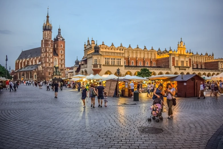a group of people walking around a town square, a photo, by Jacek Andrzej Rossakiewicz, shutterstock, at twilight, market stalls, spiky, majestic view