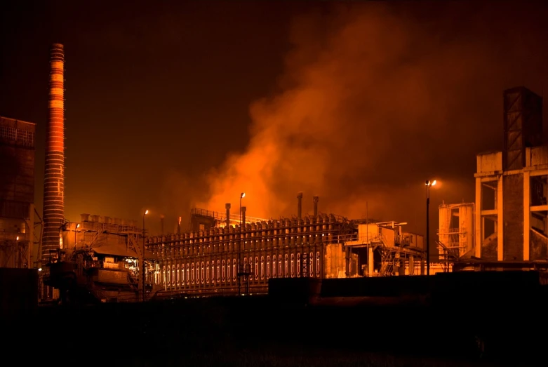 a factory with a lot of smoke coming out of it, by Werner Gutzeit, flickr, night time footage, orange fog, harsh flash photo at night, 2 0 1 0 photo