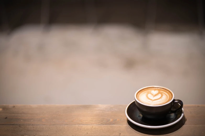 a cup of coffee sitting on top of a wooden table, by Niko Henrichon, unsplash, latte art, wallpaper - 1 0 2 4, looking left, istock