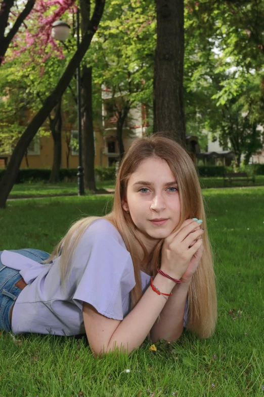 a beautiful young woman laying on top of a lush green field, a picture, by Maksimilijan Vanka, realism, dslr photo of a pretty teen girl, in a city square, taken in 2022, a girl with blonde hair