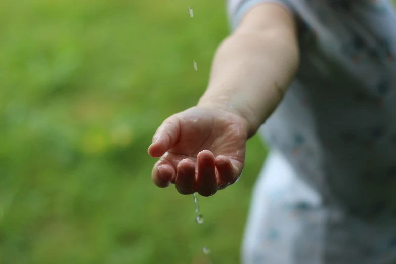 a close up of a person holding out their hand, a picture, summer rain, innocence, thirst, toddler