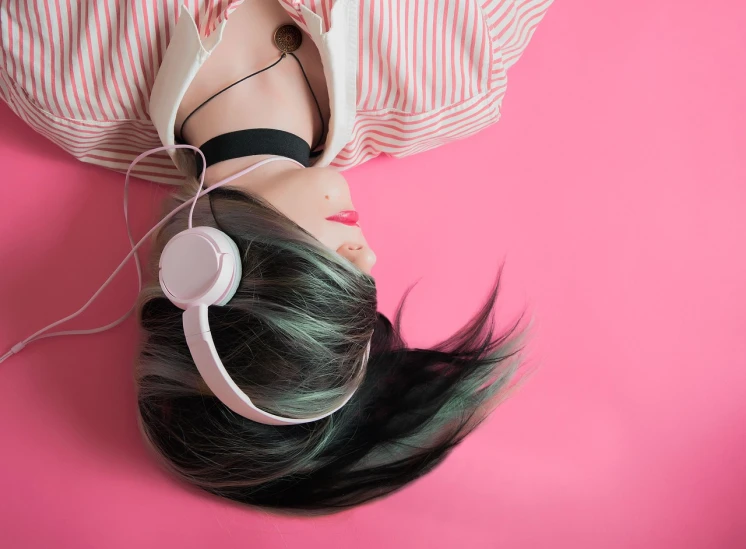 a woman with headphones laying on a pink surface, aestheticism, girl with black hair, pink white and green, music theme, istockphoto