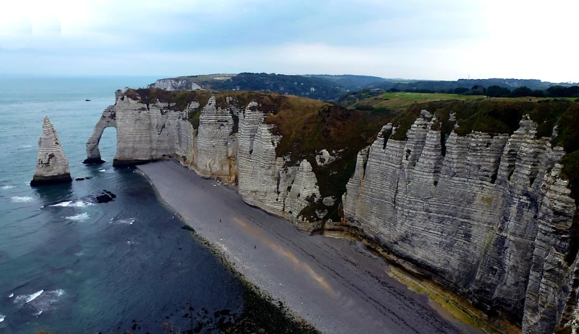 a large body of water next to a cliff, by Raphaël Collin, pexels, les nabis, drone footage, over a chalk cliff, coast as the background, 4 k film still