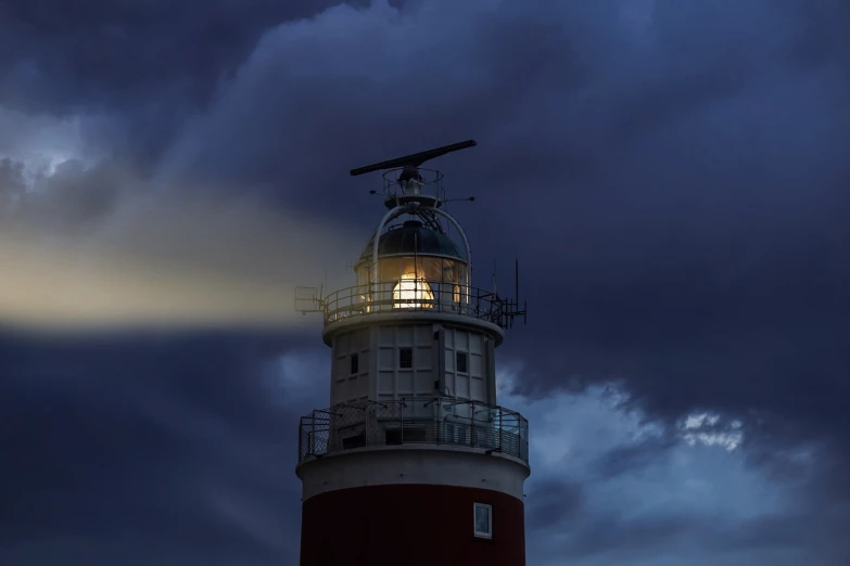 a red and white lighthouse under a cloudy sky, a picture, by Eglon van der Neer, pexels, realism, nightlight, fresnel effect, boat with lamp, the lighting is dark