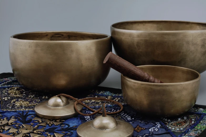 a group of singing bowls sitting on top of a table, an album cover, unsplash, mingei, metallic brass accessories, 4l, banner, shot for pottery magazine