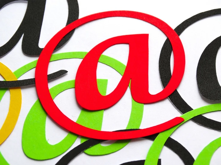 a red at sign sitting on top of a pile of green and yellow circles, a stock photo, letterism, email, vine, a horned, close - up studio photo