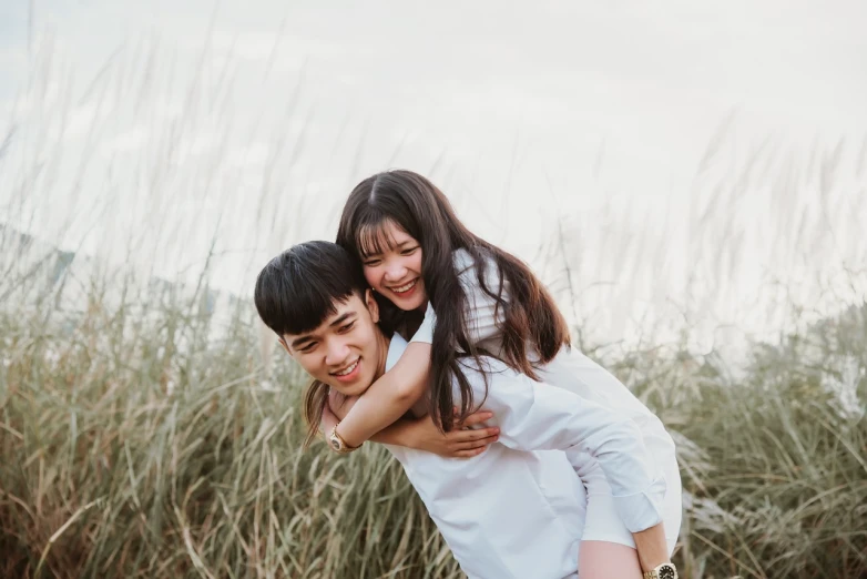 a man carrying a woman on his back in a field of tall grass, a picture, unsplash, young asian girl, miniature product photo, in a beachfront environment, close up portrait photo