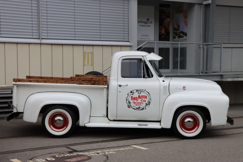 a white truck parked in front of a building, by Karl Pümpin, flickr, restomod, red wings, a wooden, speed racer