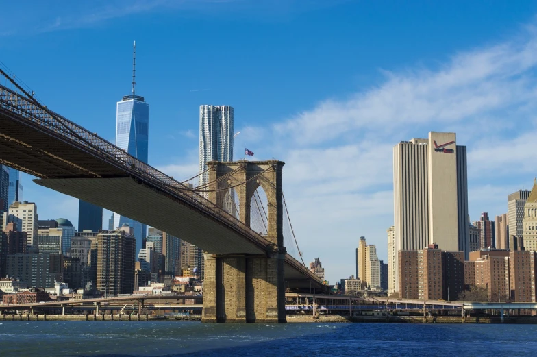 a bridge over a body of water with a city in the background, a picture, by Robert Jacobsen, shutterstock, brooklyn, low angle wide shot, during the day, two towers