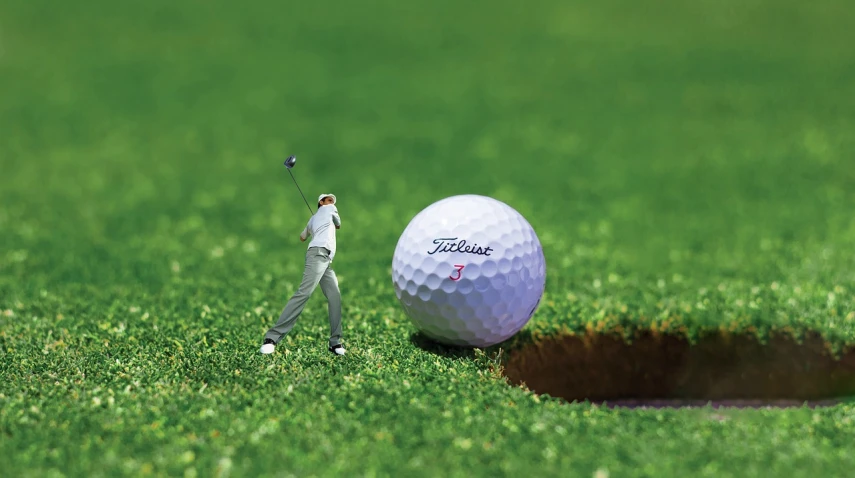 a man standing next to a golf ball near a hole, by John Armleder, photorealism, toy photography, bottom angle, competition winning, combine