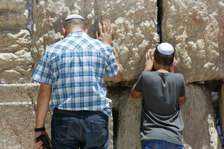 a couple of men standing next to each other near a stone wall, by Elias Goldberg, shutterstock, unilalianism, crowds of people praying, with a kid, hebrew, absolutely outstanding image