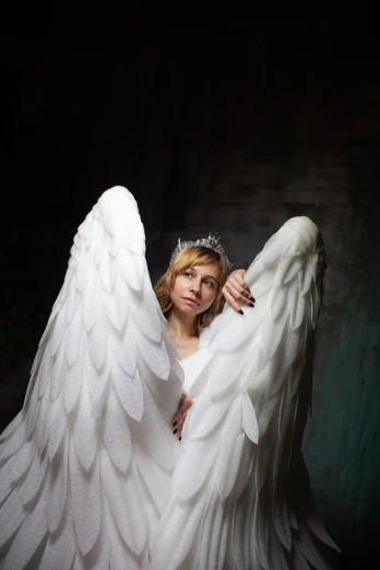a woman dressed as an angel poses for a picture, inspired by Master of the Legend of Saint Lucy, baroque, woman in a dark factory, large white wings, marketing photo, modern high sharpness photo