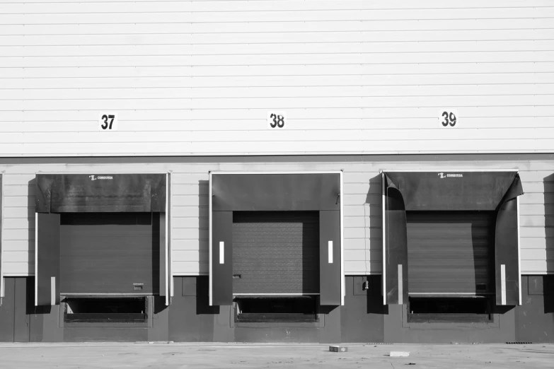 a black and white photo of a row of doors, unsplash, shipping docks, triptych, garage, ecommerce photograph