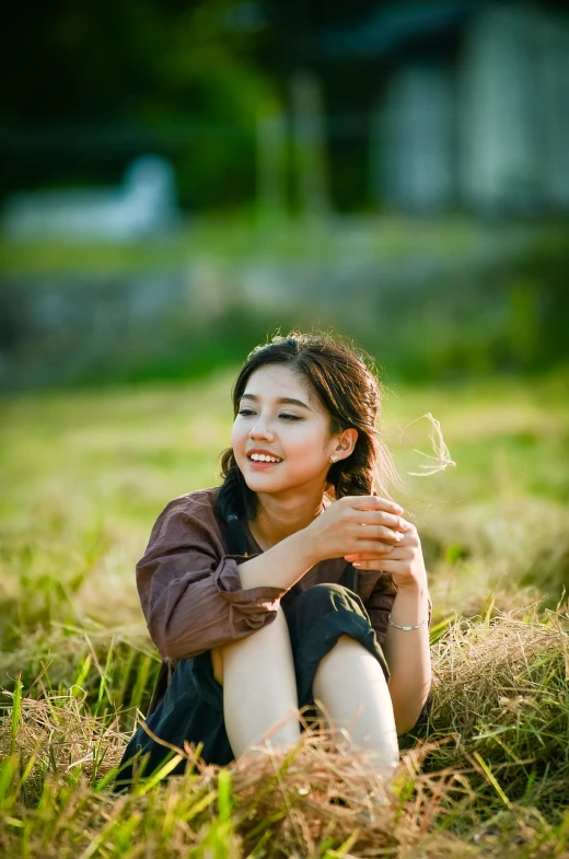 a woman sitting on top of a grass covered field, a picture, inspired by Kim Jeong-hui, shutterstock, realism, young cute wan asian face, warm light, subject is smiling, portrait mode photo