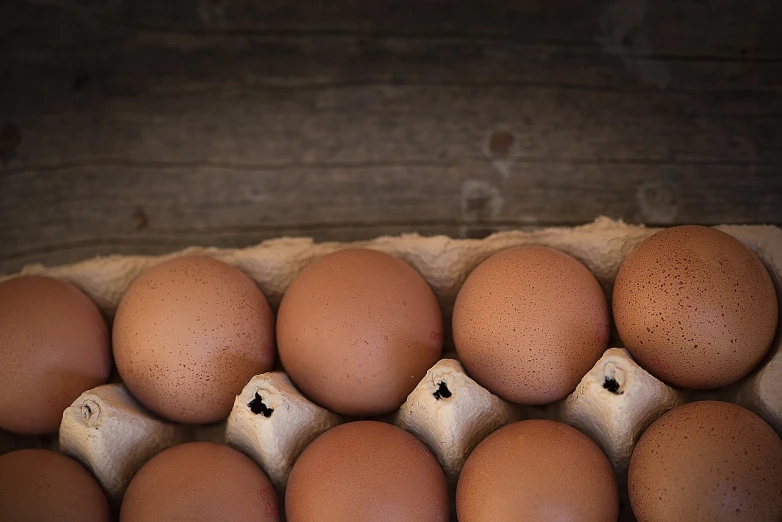 a carton filled with lots of brown eggs, a stock photo, renaissance, edge vignette, bottom body close up, on a wooden plate, half and half