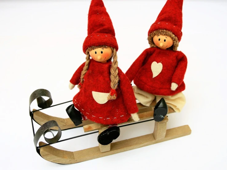 a couple of dolls sitting on top of a sled, by Marie Angel, reds, product photo, medium detail, elves