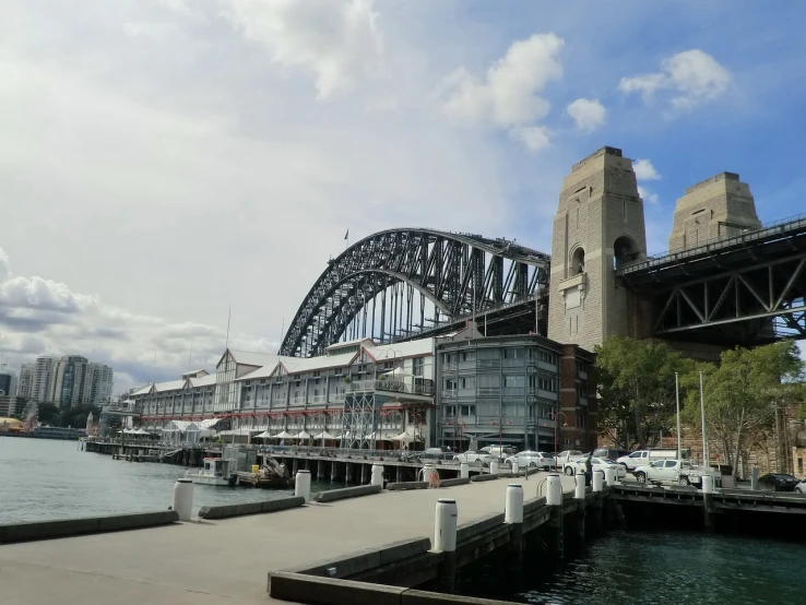 a large bridge over a body of water, a picture, inspired by Sydney Carline, shutterstock, hurufiyya, viewed from the harbor, tall terrace, docked at harbor, tony roberts